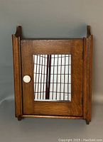 Front view of antique wooden medicine cabinet with mirrored door and round white knob.