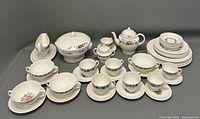 Full overview of two partial Wedgwood china sets with assorted cups, saucers, plates, covered bowl, sugar bowl, creamer, and teapot with floral patterns.