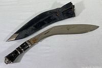 Photo showing the full kukri knife and its black leather sheath with metal tip end