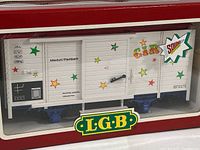 Front view of the LGB circus-themed G scale boxcar in original packaging showing colorful star decals, CIRCUS lettering and sound feature badge.