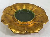 Angled view of gold leaf flower-shaped pottery ashtray with green center and cigarette notches
