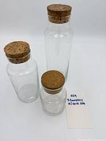 front view of three glass canisters with cork lids