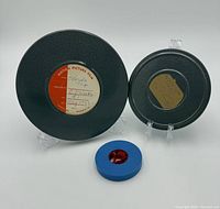 Two metal reels with labels and plastic reel displayed on stands
