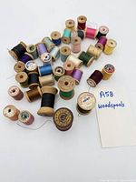 Group of about 35 wooden spools with coloured threads