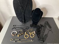 Overview of costume jewelry collection including necklaces, bracelets, and earrings arranged on a table with black display busts