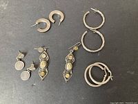 Group shot of all six pairs of silver earrings on black background to show overall lot content.