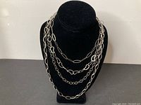 Front view of sterling silver necklace on black velvet bust showing four different chain styles linked together.