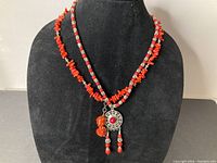 Two necklaces displayed on black jewelry bust stand with necklace pendants clearly visible.