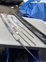 Four antique cutting tools laid out on table next to a large sheath showing overall condition and relative sizes.
