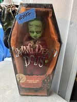 Photo of the Living Dead Dolls Ernest Lee Rotten doll still in original coffin-shaped box with visible wear on the plastic front.