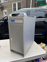 Front angle view of Apple Power Mac G5 computer tower with perforated aluminum front panel and slot-loading optical drive.