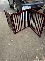 Pet gate fully extended, showing three panels with vertical slats and hinged connections.