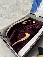 Pair of velvet maroon Air Jordan 1 Retro Heiress sneakers with gold Swoosh inside original box