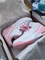 One shoe out of the box showing white leather and pink accents, perforations, pink laces, cushioned sole with visible air unit