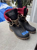 Pair of black and tan ladies winter boots with dark red fleece lining, beige laces, and Storm by Cougar label on the tongue.