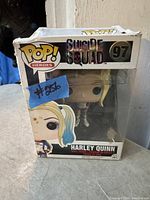 Photo showing the front and top of the original Pop! Heroes Suicide Squad box containing Harley Quinn figure #97 with visible box edge wear and a blue sticker with number #856 on the front.