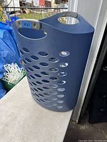 Blue Rubbermaid clothes hamper with oval holes and two side handles