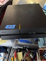 Top view of black Sony PS4 console with blue "#153" sticker
