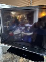 Photo showing the Toshiba 40-inch flat screen TV powered on displaying 'No Video Signal' message, black frame and stand visible.