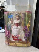 Photo of a vintage Walt Disney Mary Poppins doll in original box. Doll wears white and red attire with white cape and hat. Box has carousel horse decorations and 'Walt Disney Mary Poppins' on front. Box is visibly worn and damaged.