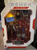 Photo of Roman Reigns wrestling action figure in original sealed box including multiple interchangeable hands and two championship belts