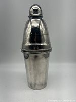 Front view of the full bullet-shaped silver plate cocktail shaker with cap, showing step details on the top cone portion and smooth bottom shaker cup.