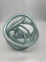 Full view of the art glass knot sculpture showing intertwined loops and smooth finish