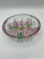 Top down view showing the pink poinsettia flower and green leaves on clear glass.