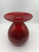 Front view showing bulbous red glass vase with wide flared top.