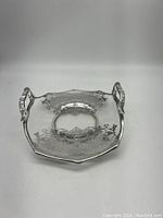 Front angle view of the octagonal clear glass dish with silver overlay floral and geometric designs, featuring two ornate silver handles.