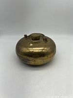 Full frontal view of the vintage brass hot water bottle with visible tarnish and scratches.