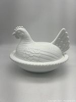 Front and side angle view of the milk glass hen on nest covered dish showing detailed hen lid atop nest base with beaded edge.