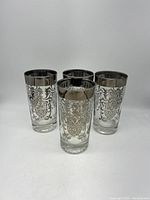 Four vintage Kimiko glasses with platinum scroll design and silver band rimmed tops arranged on white background.