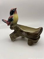 Side view showing the bird figurine on the tree stump planter with Royal Copley label.