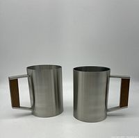 Two vintage Hongern pewter mugs with wood inlay handles side by side on a white background