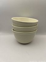 Stack of three vintage white stoneware bowls showing shape, size and finish.