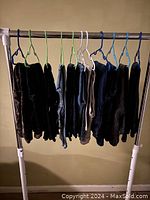 Eleven pairs of boys jeans hanging on plastic hangers on a rack. Pants vary in shades including dark, medium, and light denim.