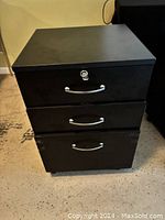 Front view of black 3 drawer office cabinet with silver handles and lock on top drawer.