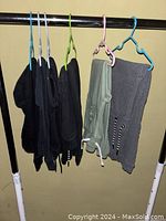 Six pairs of boys' sweatpants hanging on hangers showing variety of colors and logos.