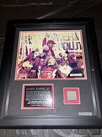 Black framed memorabilia showing Kasey Kahne celebration photo, certificate, and tire piece.