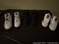 Front and side view of three pairs of boys sneakers: 2 Jordans (black and white) and 1 white Adidas without laces