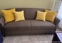 Front view of brown sofa with four yellow pillows, showing overall condition and style.