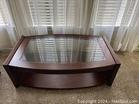 Top front angle showing entire coffee table with wooden frame and glass top with lower wooden shelf