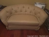 Front view of the beige fabric curved sofa showing tufted backrest and single cushion seat