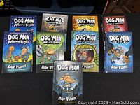 9 Dog Man series books arranged on a table surface, showing colorful illustrated covers.