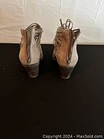 Back view of mid tan fringe boots showing zippers and stacked heel details.