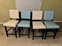 Four high top chairs with black legs and frames; two chairs with light blue upholstery and two with white upholstery.