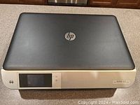 Closed HP Envy 5535 printer showing overall top and front design with HP logo and touchscreen panel.