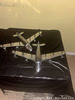 Two metallic silver airplane models placed on black fabric background, angled to show wings and body details.