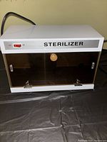 Front view of closed UV sterilizer unit with on/off switch and tinted front door with knob.